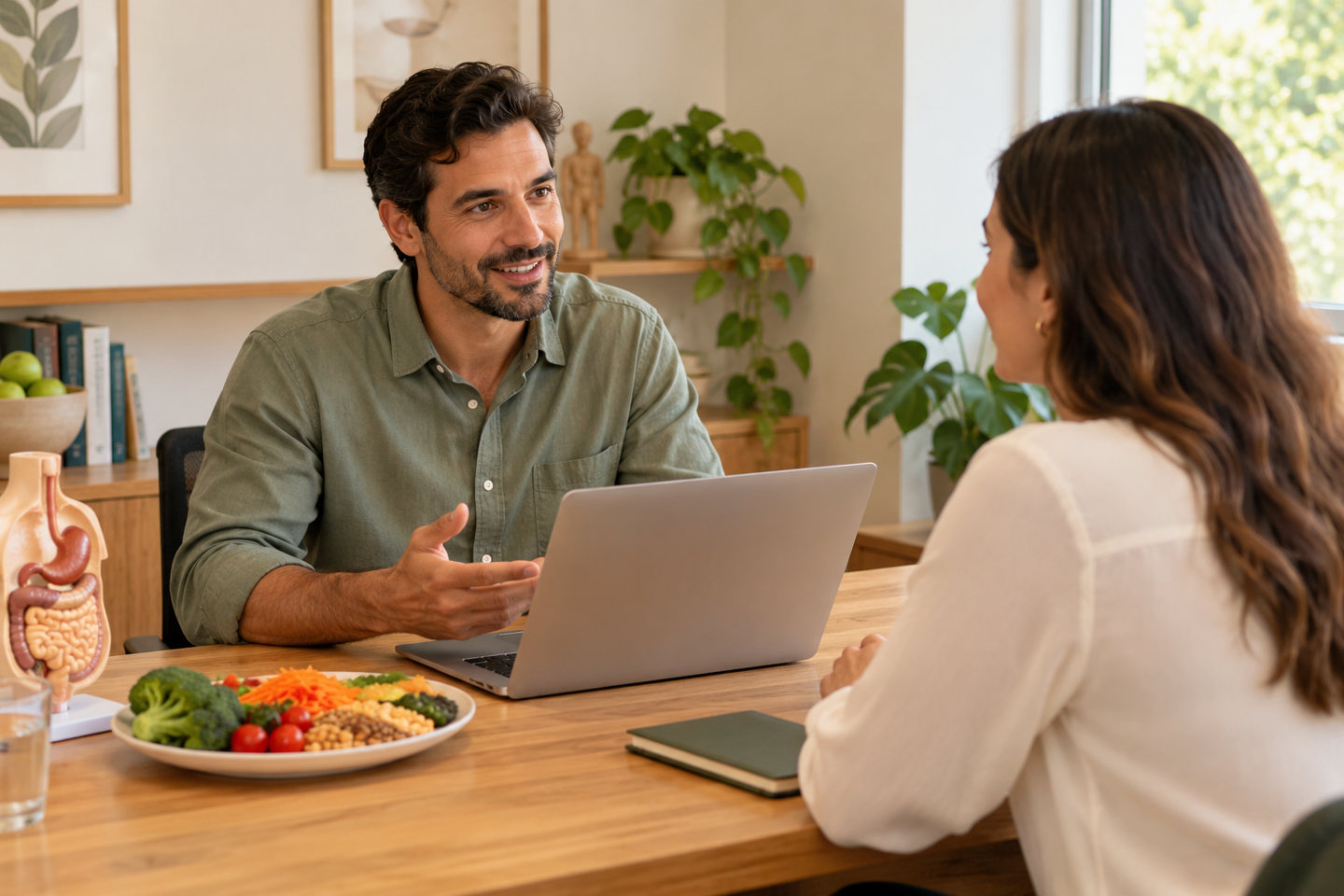 Nutricionista usa o notebook durante uma conversa com a cliente no consultório.