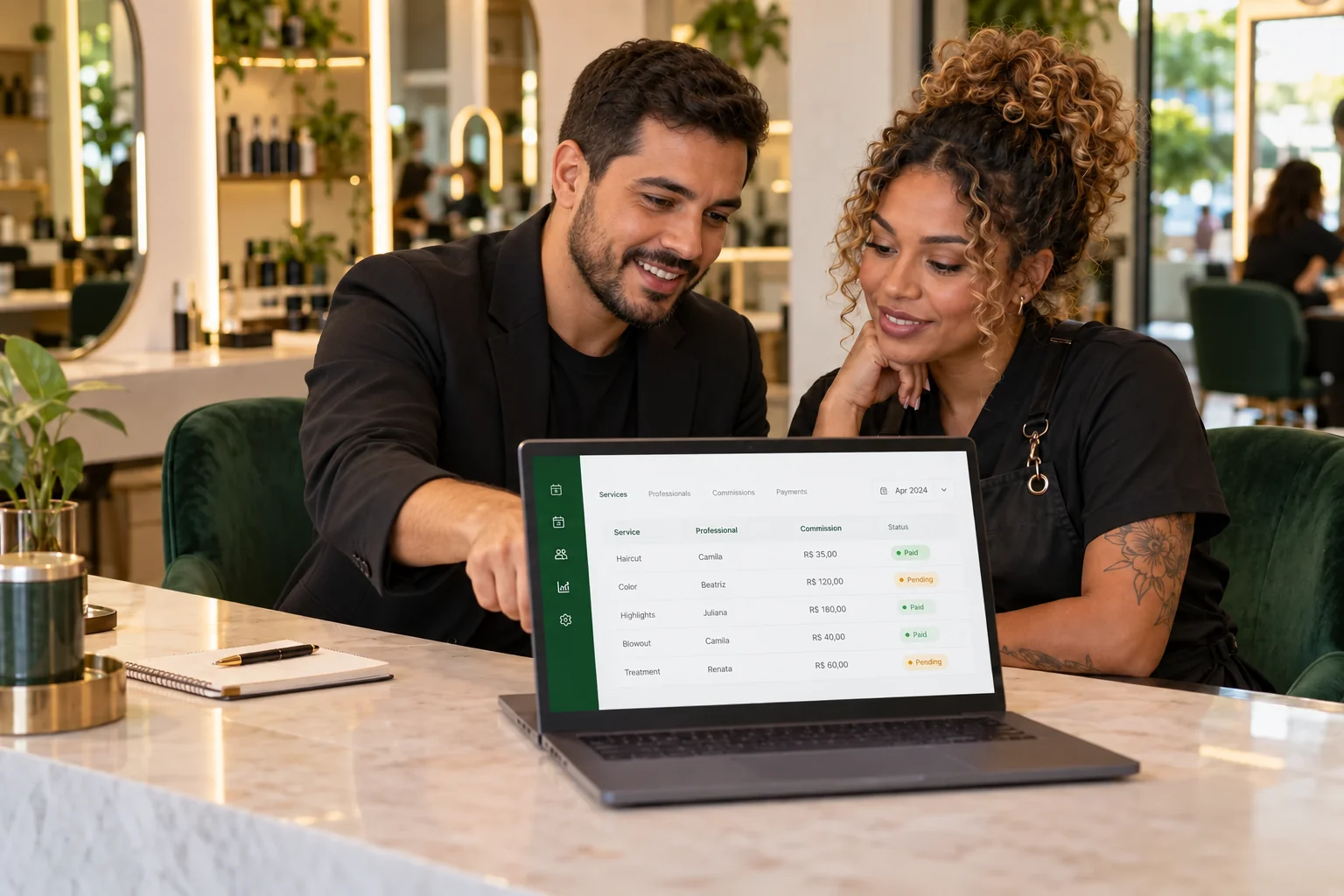 Gestor e profissional de salão conferindo uma tabela de comissões em um notebook